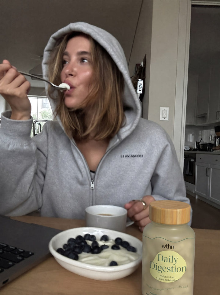 Eating yogurt at the kitchen table, a bottle of Daily Digestion beside the bowl